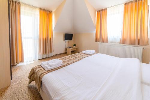 ein großes weißes Bett in einem Zimmer mit Fenstern in der Unterkunft Ring Hotel in Blagoewgrad