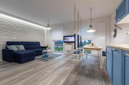 a living room with a blue couch and a kitchen at Goma Rent - Angielska Grobla City Centre in Gdańsk