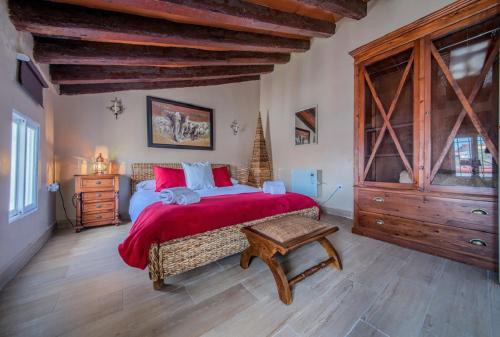 ヘレス・デ・ラ・フロンテーラにあるアパルタメントス ヘレスのベッドルーム1室(赤いシーツと木製の天井の大型ベッド1台付)