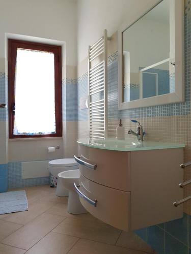 une salle de bain avec un lavabo, des toilettes et un miroir dans l'établissement Appartamento tra mare e montagna, à Baunei