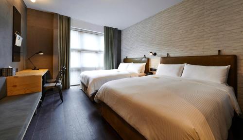 a hotel room with two beds and a desk at Just Sleep - Sanchong in Taipei