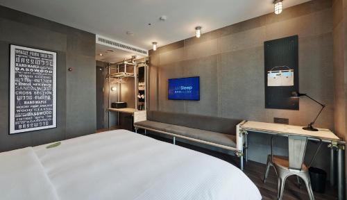 1 dormitorio con cama, banco y TV en Just Sleep - Sanchong en Taipéi