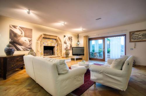 a living room with two white chairs and a fireplace at Villa Zagara Garden Spectacular Sea View in Taormina in Taormina