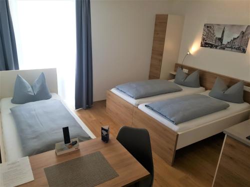 a small room with two beds and a table at easy sleep Apartmenthotel in Landshut