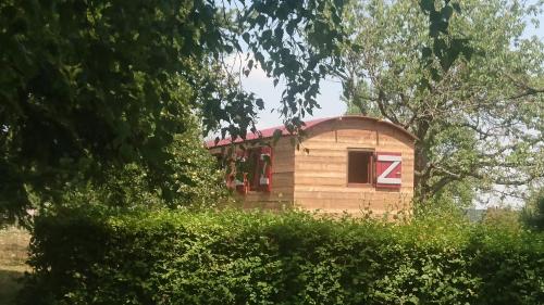 a small house in the middle of some trees at LA ROULOTTE DES AMISH & Bain Nordique à Remous Jacuzzi in Mattexey
