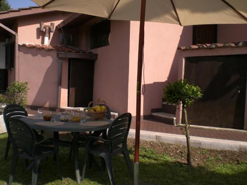 a table with chairs and an umbrella in front of a house at Villa di Christian e Michelle in Rome