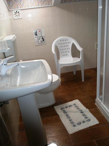 a bathroom with a sink and a toilet and a chair at Alojamento Local Céu-Azul in Porto de Mós