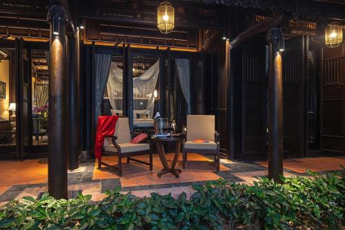 a patio with two chairs and a table in a building at Ancient Huế Garden Houses in Hue