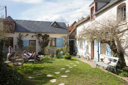 ミタンヴィルにあるMaison d'Hotes à l'Ombre Bleueの家の庭に座る二人