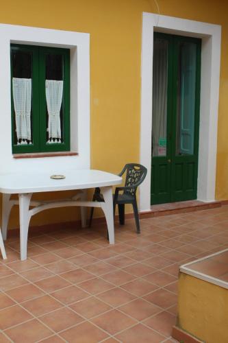 a table and a chair next to a green door at Le Chiazzette in Acireale