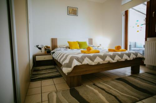una camera da letto con un letto con cuscini gialli e una finestra di Petros apartmani a Vukovar