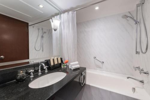 
a bathroom with a sink, mirror, and bathtub at Marco Polo Hongkong Hotel in Hong Kong
