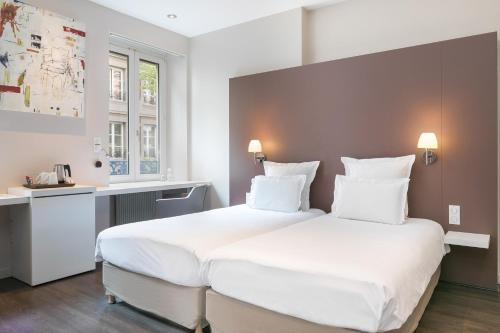a bedroom with a large white bed with white pillows at Hôtel de l'Europe by HappyCulture in Strasbourg