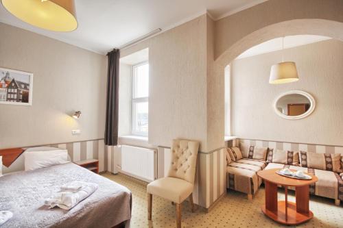 une chambre d'hôtel avec un lit et un canapé dans l'établissement Inza Hotel, à Druskininkai