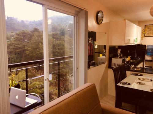 a kitchen with a large window and a table with a laptop at Courtyards Peak-Corner Pinestay - at Goshenland Baguio in Baguio