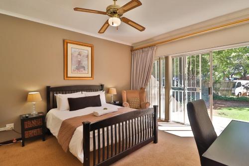 - une chambre avec un lit et un ventilateur de plafond dans l'établissement Fin and Feather Guest Lodge, à Boksburg