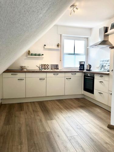 a kitchen with white cabinets and a wooden floor at Ferienwohnung Xanten in Xanten