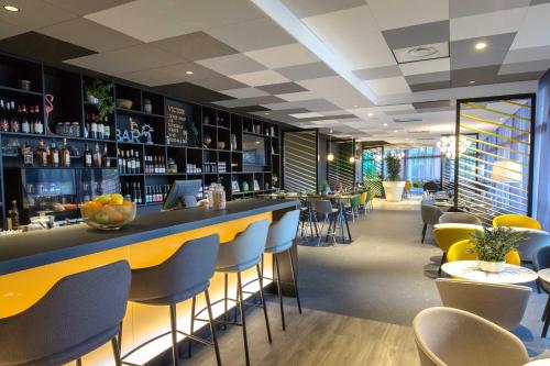 a bar in a restaurant with yellow and blue chairs at Mercure Hyères Centre Côte d'Azur in Hyères