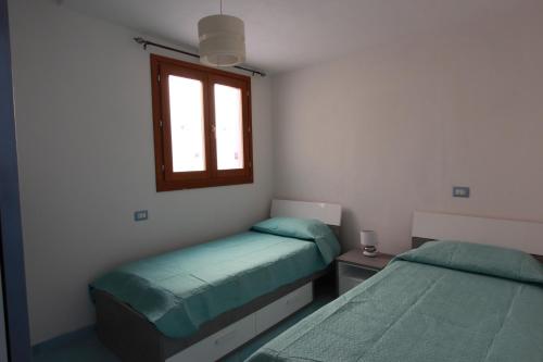 una camera con 2 letti singoli e una finestra di Via Del Mare a Budoni