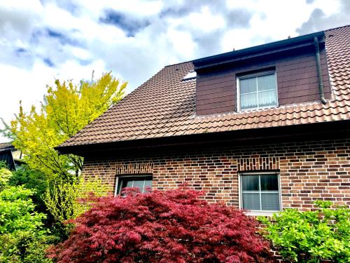 een stenen huis met een rode struik ervoor bij Ferienwohnung Xanten in Xanten