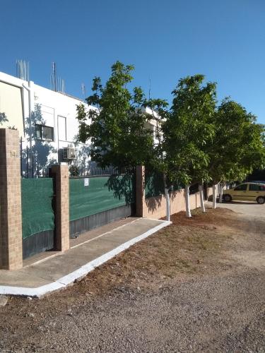 a building with a fence with trees in front of it at Nina Rooms (apartments) in Artemida