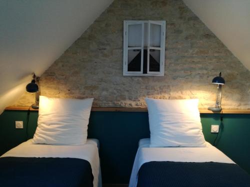 2 Betten in einem Zimmer mit Fenster in der Unterkunft Atelier aux Dimes in Le Manoir
