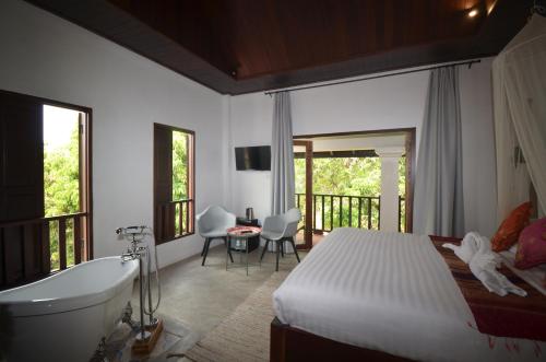 a bedroom with a bed and a bath tub and a tub at Moonlight Champa Riverview in Luang Prabang