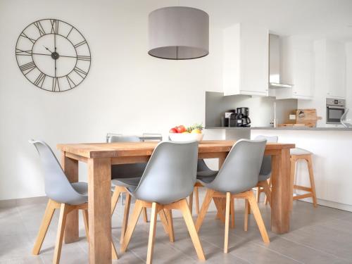 a kitchen with a wooden table with chairs and a clock at Château Les Merles et ses Villas in Mouleydier