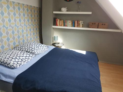a bedroom with a blue bed and a book shelf at La Casa Céline in Surtainville