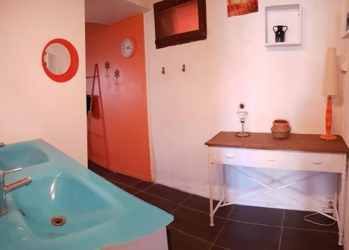 La salle de bains est pourvue d'une baignoire bleue et d'un lavabo. dans l'établissement La Casa Céline, à Surtainville