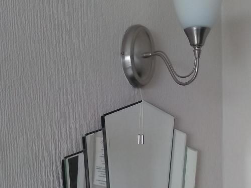 a light on a wall next to a shelf with boxes at The Iverna in Eastbourne