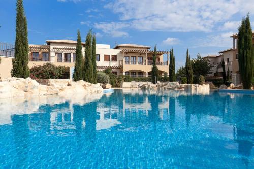 a large pool of blue water in front of a house at Aphrodite Hills Rentals - Premium Serviced Apartments in Kouklia