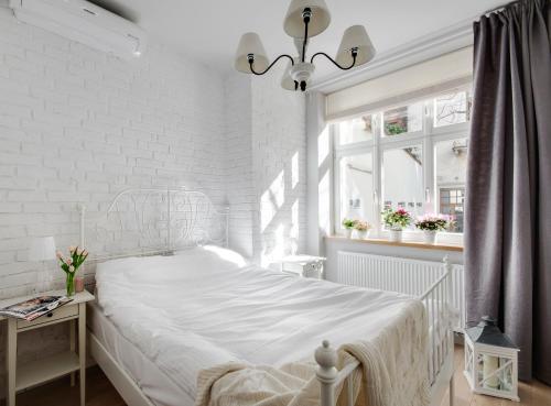 a white bedroom with a bed and a white brick wall at Too-Good Premium Apartments in Krakow