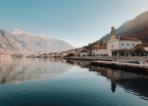 a river with a church next to a mountain at Djurovic Apartments Montenegro in Kotor