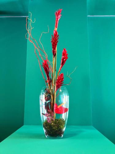 a glass vase with red flowers in it at Hotel Ritual Maspalomas - Adults Only in Playa del Ingles