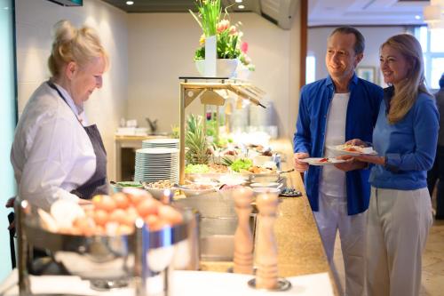 a man and a woman holding a plate of food at A-ROSA Ostseehotel Kühlungsborn in Kühlungsborn