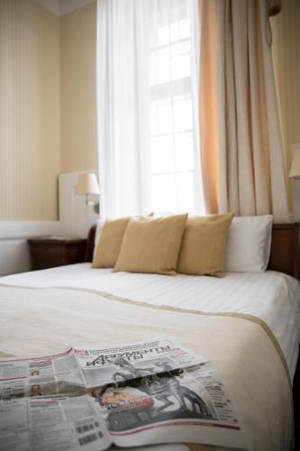 a bedroom with a bed with a newspaper on it at Erzsébet Nagy Szálloda in Paks