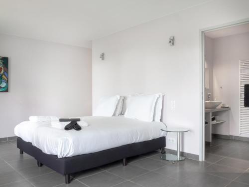 a white bedroom with a large white bed with a table at Château Les Merles et ses Villas in Mouleydier