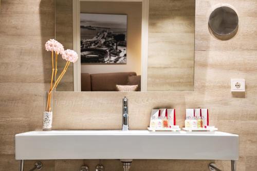 a bathroom with a mirror, sink, and bathtub at Salles Hotel Málaga Centro in Málaga