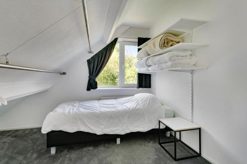 a white bedroom with a bed and a window at Mosselbank 073 - Noordzeepark Ouddorp in Ouddorp