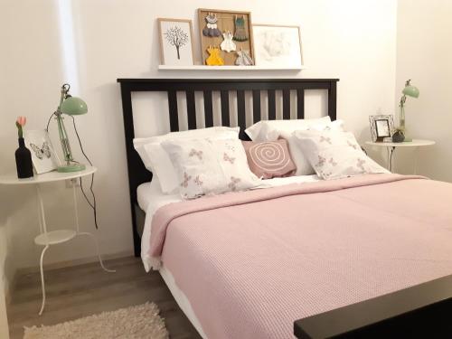 - une chambre avec un lit doté de draps roses et d'oreillers blancs dans l'établissement Apartments Kule, à Brela