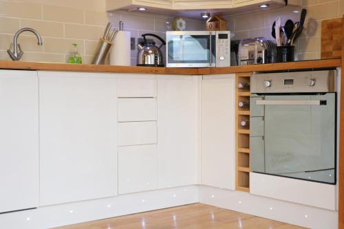 a kitchen with white cabinets and a counter with a microwave at TOWN CENTRE contemporary cottage in Padstow