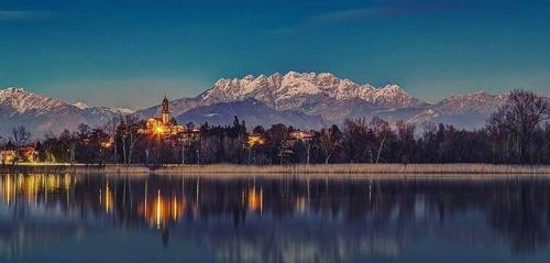 a large body of water with a church and snowy mountains at B&B Il Portico del Conte in Bosisio Parini