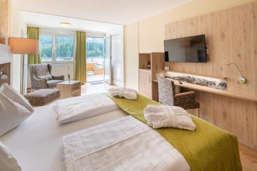トゥルラッハー・ヘーエにあるPanorama Hotel Turracher Höheのベッド2台とテレビが備わるホテルルームです。
