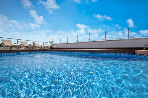 una gran piscina con sillas y un cielo azul en Salles Hotel Málaga Centro, en Málaga