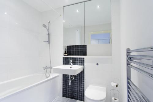 Baño blanco con lavabo y aseo en Abodebed KD Tower en Hemel Hempstead