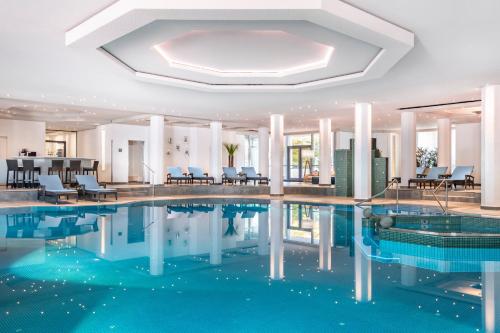a pool in a hotel with chairs and tables at The Westin Grand Munich in Munich