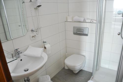 a white bathroom with a toilet and a sink at Gasthof Adler Güttingen in Güttingen