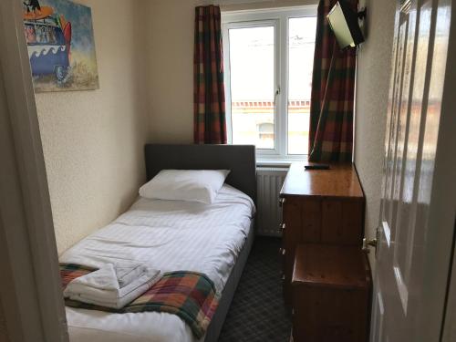 a small bedroom with a small bed and a window at The Sherborne Lodge in Ilfracombe