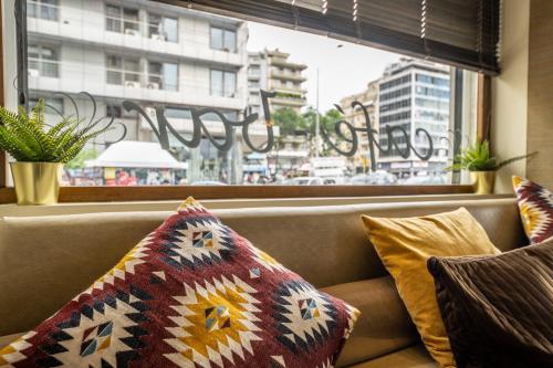 a couch with pillows sitting in front of a window at Abc Hotel in Thessaloniki
